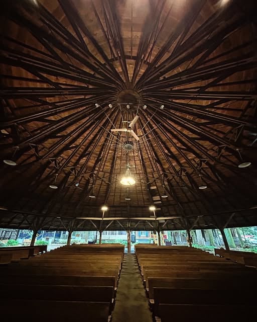 Inside the Mt. Gretna Tabernacle: rows of wooden pews beneath a radial web of ceiling trusses